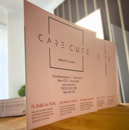 Ein weißes Schild mit schwarzer Schrift, dem Care Cute-Logo, Kontaktdaten und Angeboten.